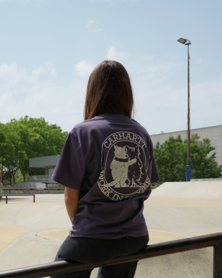 Femme portant un t-shirt violet et un pantalon noir de la marque Carhartt.