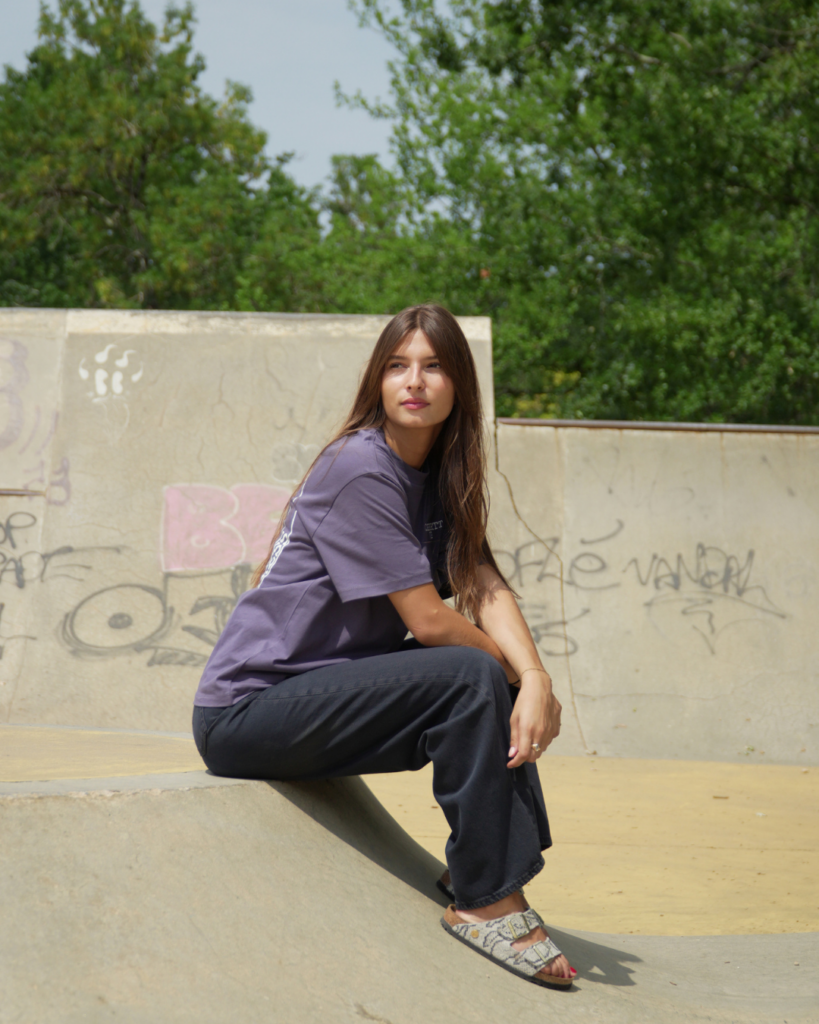 Femme portant un t-shirt violet et un pantalon noir de la marque Carhartt.